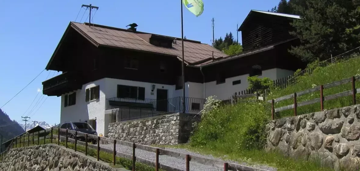 Außenansicht der Faultierfarm mit wehender Fahne an einem sonnigen Sommertag