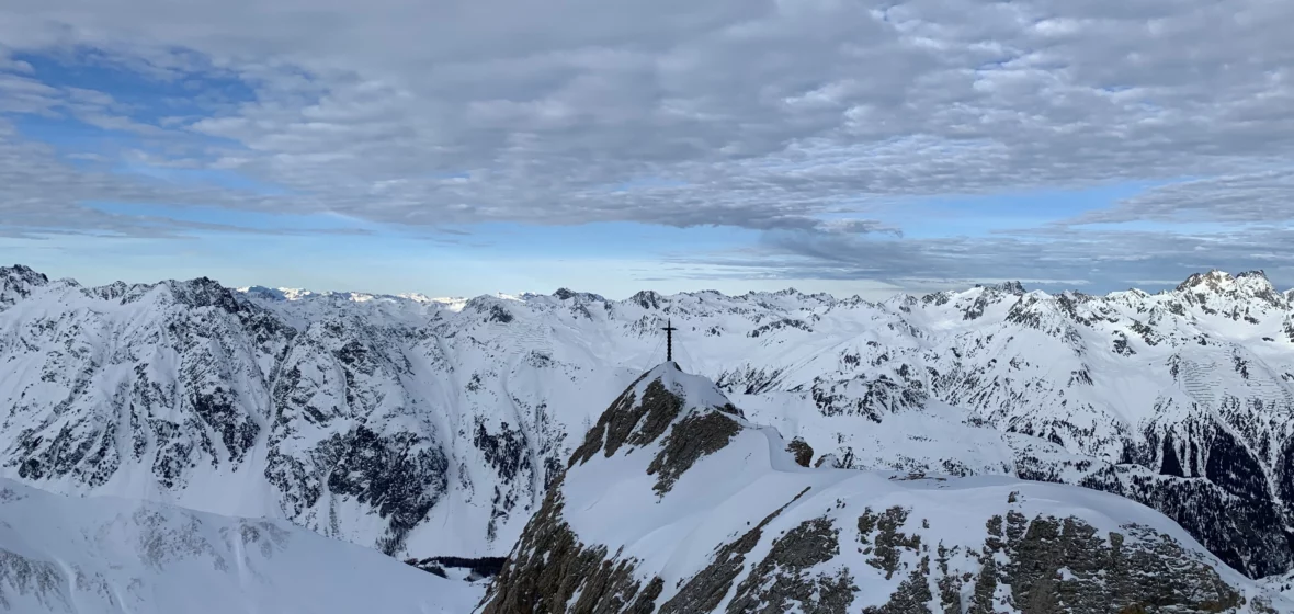 Panoramablick vom Gipfelkreuz über verschneite Berge im Skigebiet